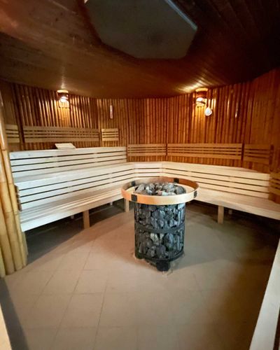 Kamenný ohrievač sauny obklopený bambusovými lavicami